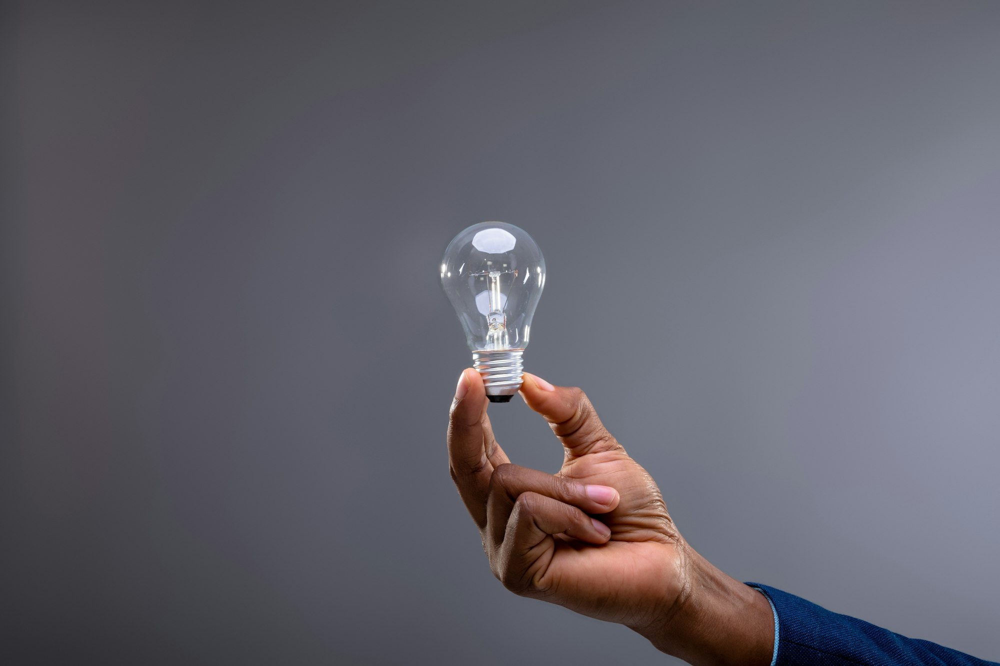 Close up of businessman holding light bulb against grey background